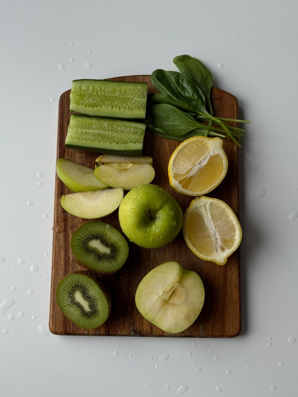 Fresh green apple, kiwi, cucumber, spinach and lemon arranged on a wooden board